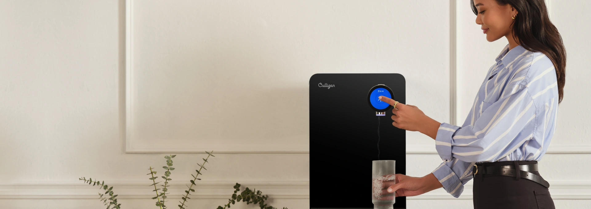 Frau bedient einen Culligan Wasserspender im Büro und hält ein Glas Wasser in der Hand